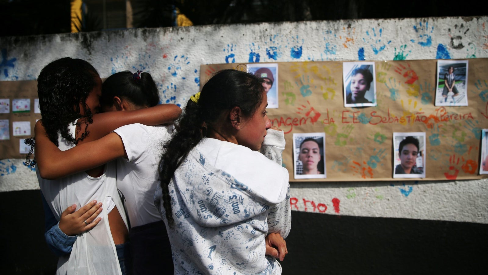 A photo of students crying in front of pictures of the victims shooting at the Raul Brasil school.