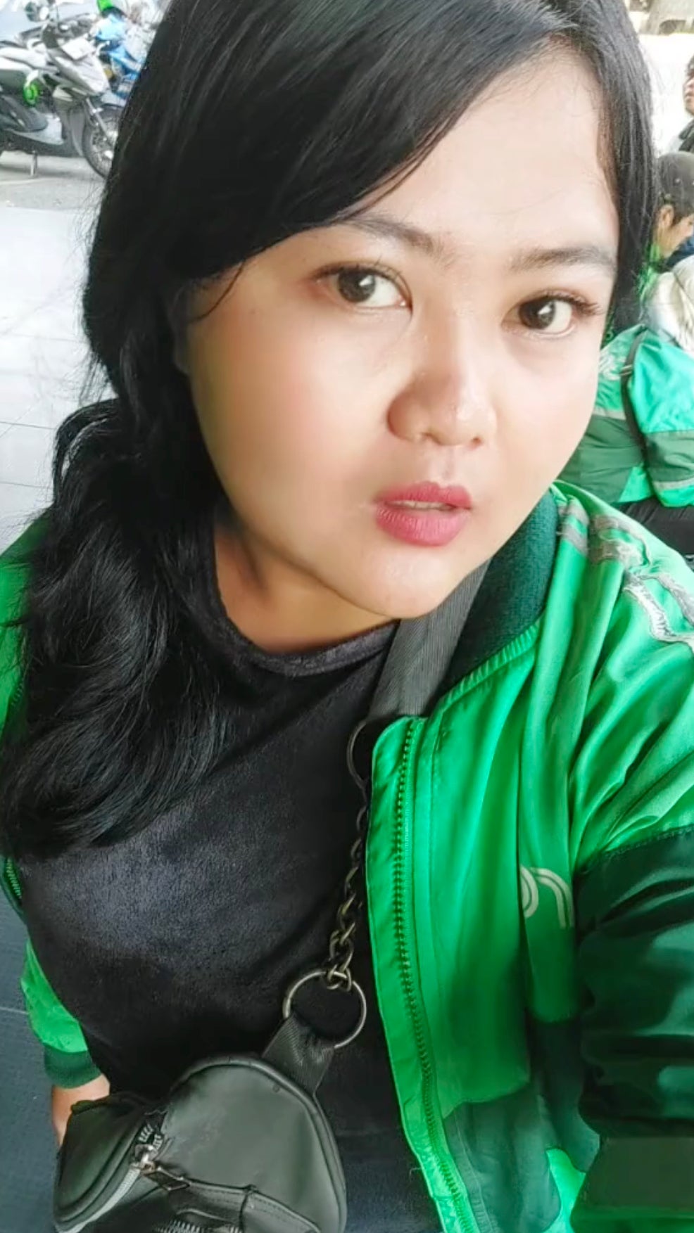 A screenshot of a TikTok video showing a woman with black hair wearing a green jacket speaking to the camera.