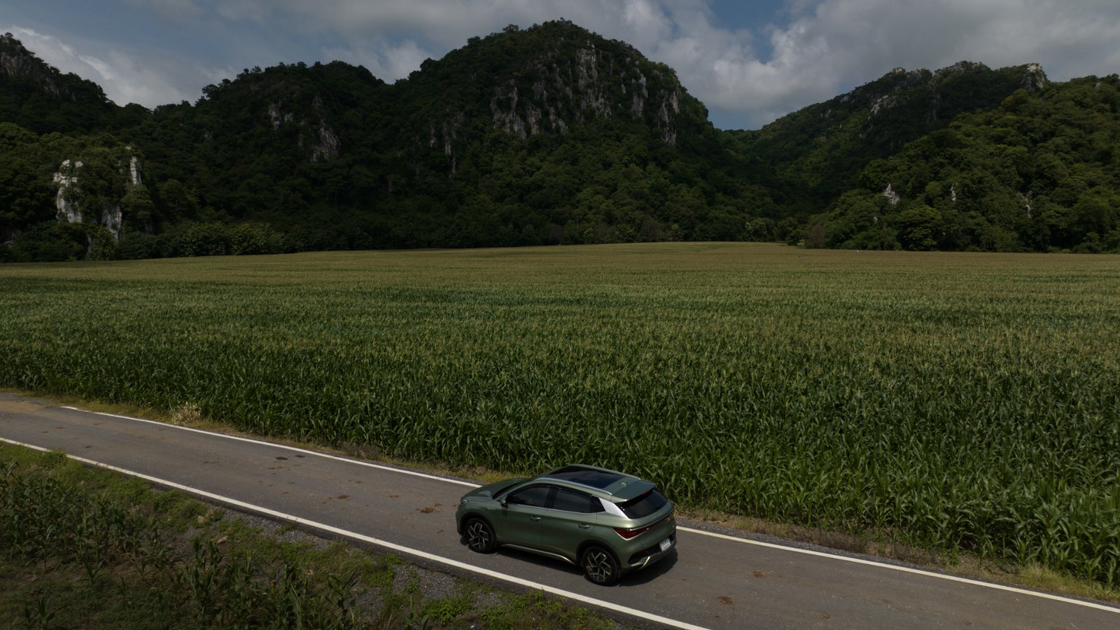 An aerial photo of the BYD Atto-3 against a green mountain landscape in Thailand.