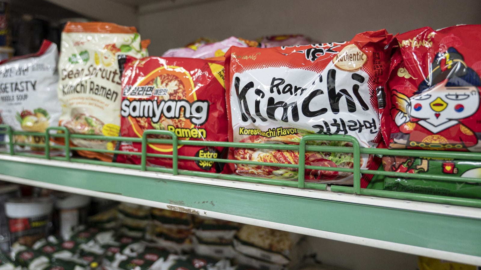 A photo showing packages of ramen for sale on a shelf at a grocery store.