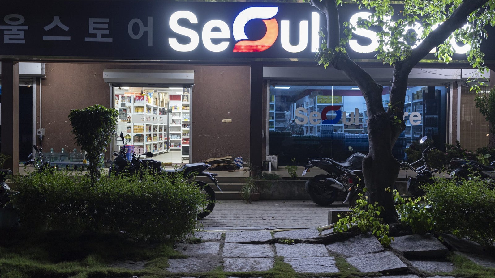 A photo showing the exterior of a grocery store with signage in English and Korean, at night.
