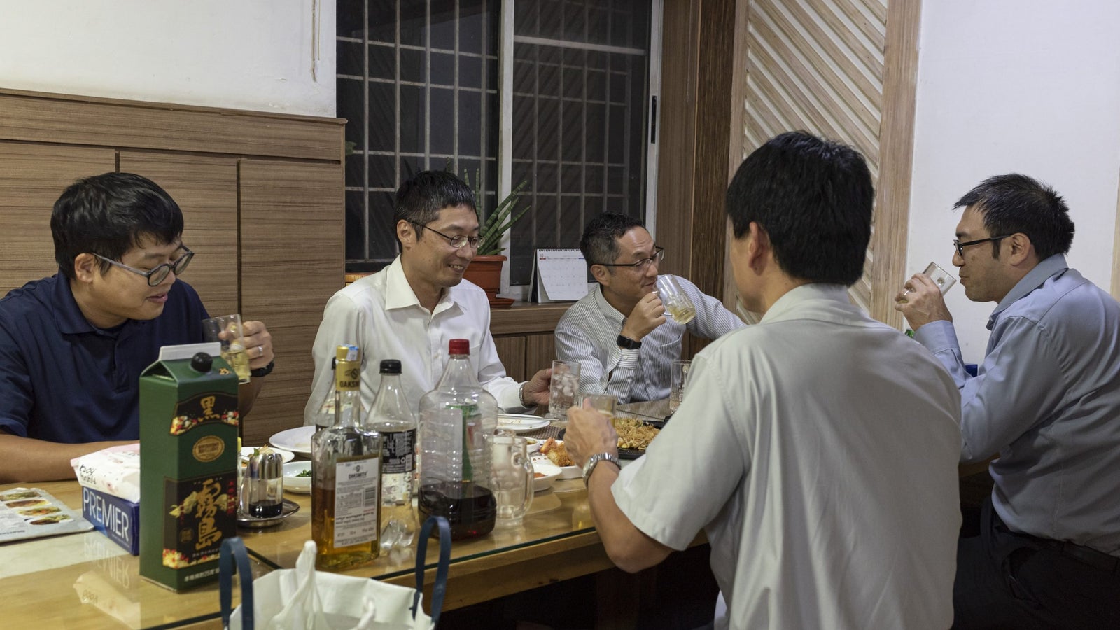 A photo showing a group of men eating and drinking at a restaurant.