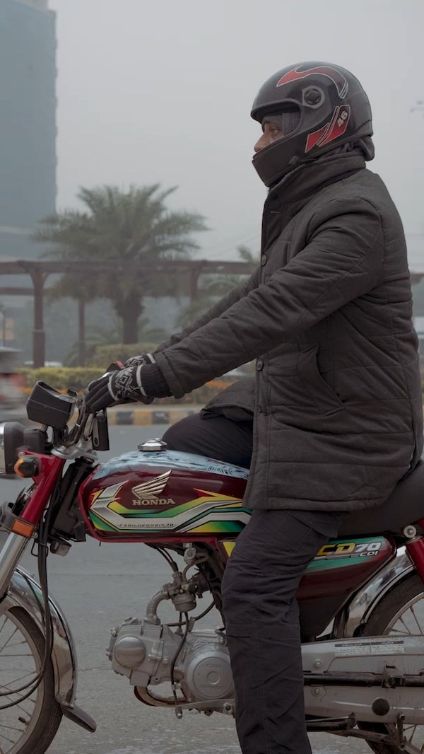 A photo of a man sitting on a motorbike on a busy street in Lahore, Pakistan.