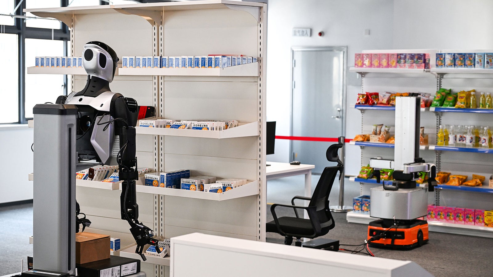 A humanoid robot stands near shelves stocked with products in a modern store setting, with another robot in the background.