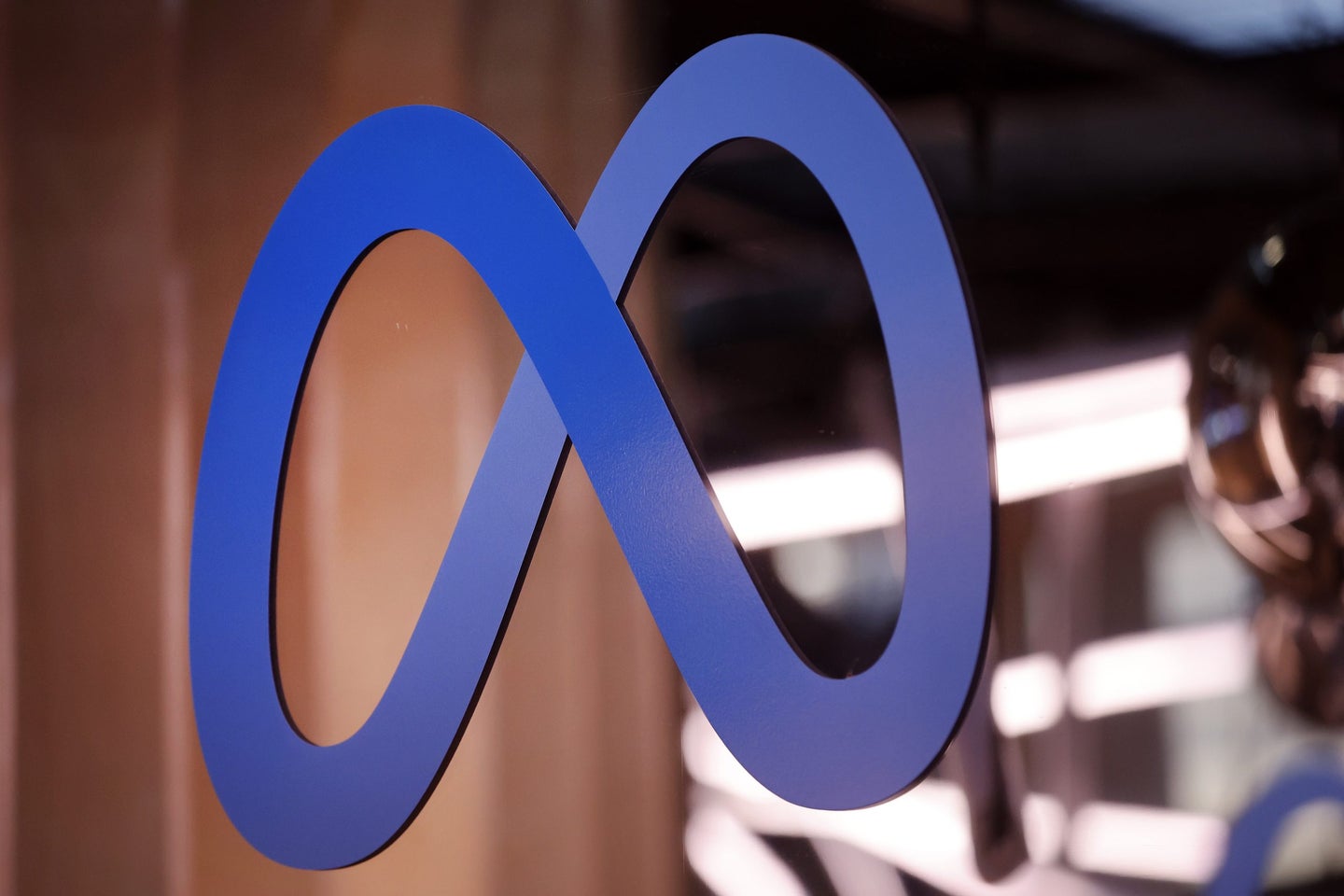 A blue infinity symbol logo representing Meta, set against a blurred background.