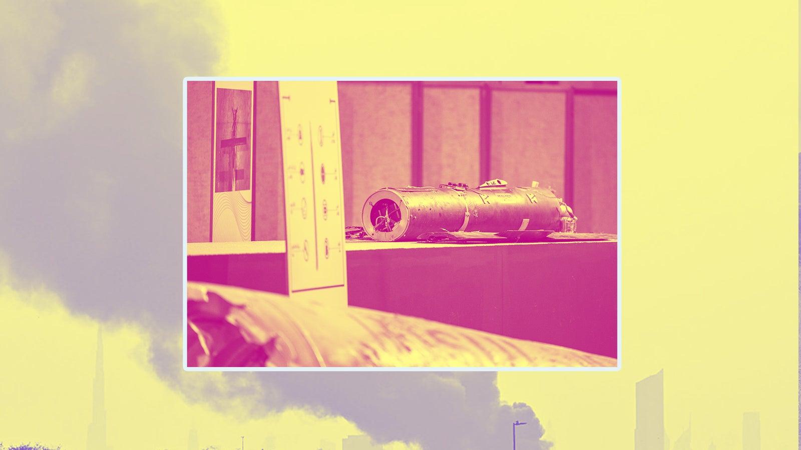 A metallic object, possibly a torpedo or weapon, displayed on a pedestal with a blurred cityscape in the background.