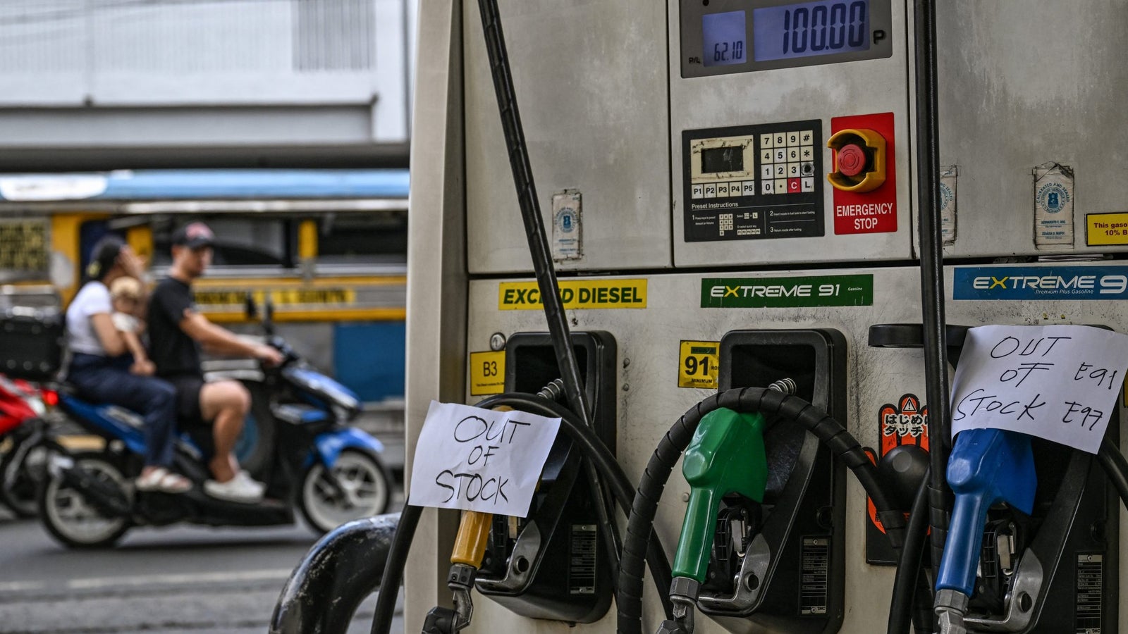 Fuel pump with signs stating "Out of Stock" for Extreme Diesel and Extreme 91, while a motorcycle passes by.