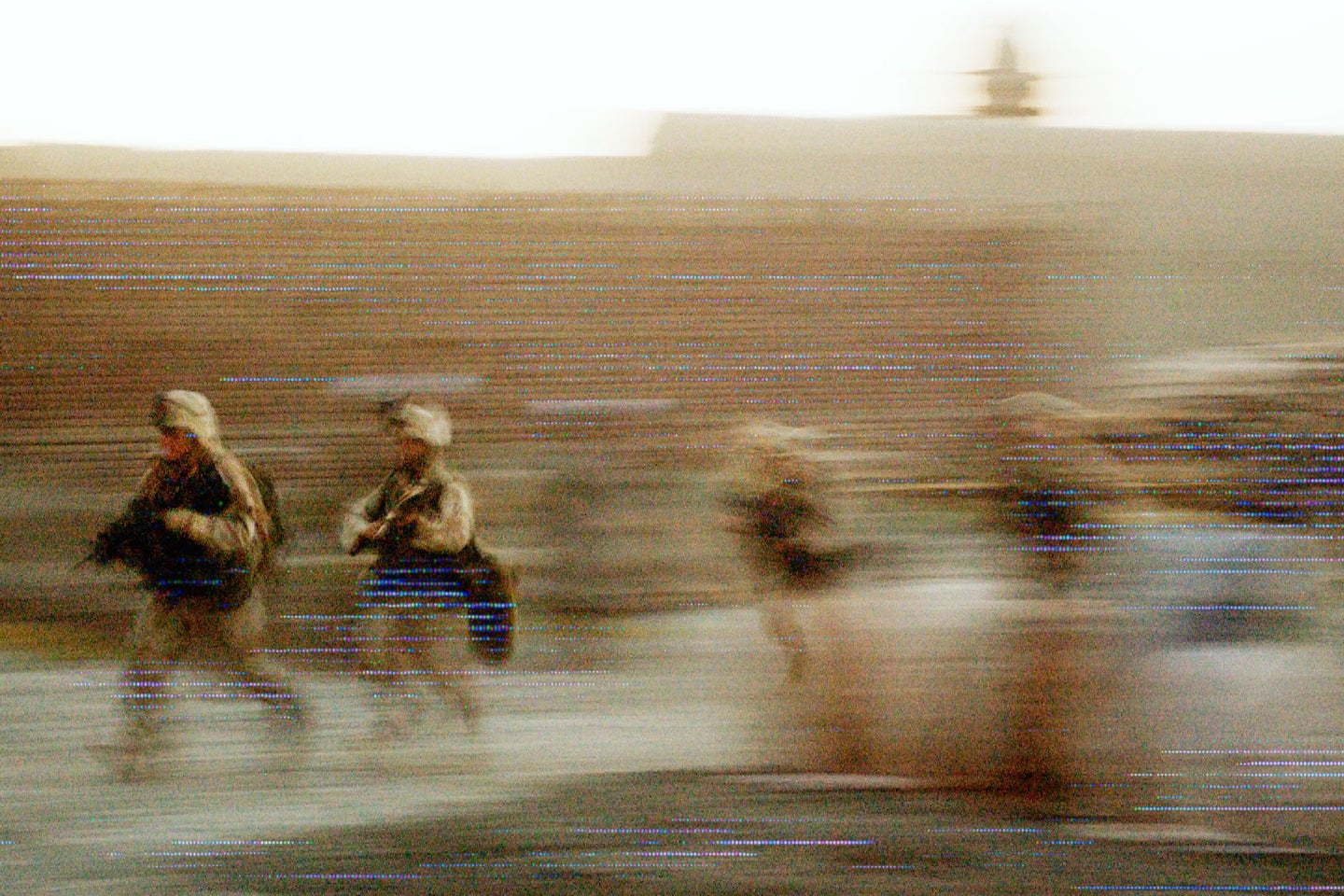 Blurred image of soldiers running, creating a sense of motion with a warm, faded background.