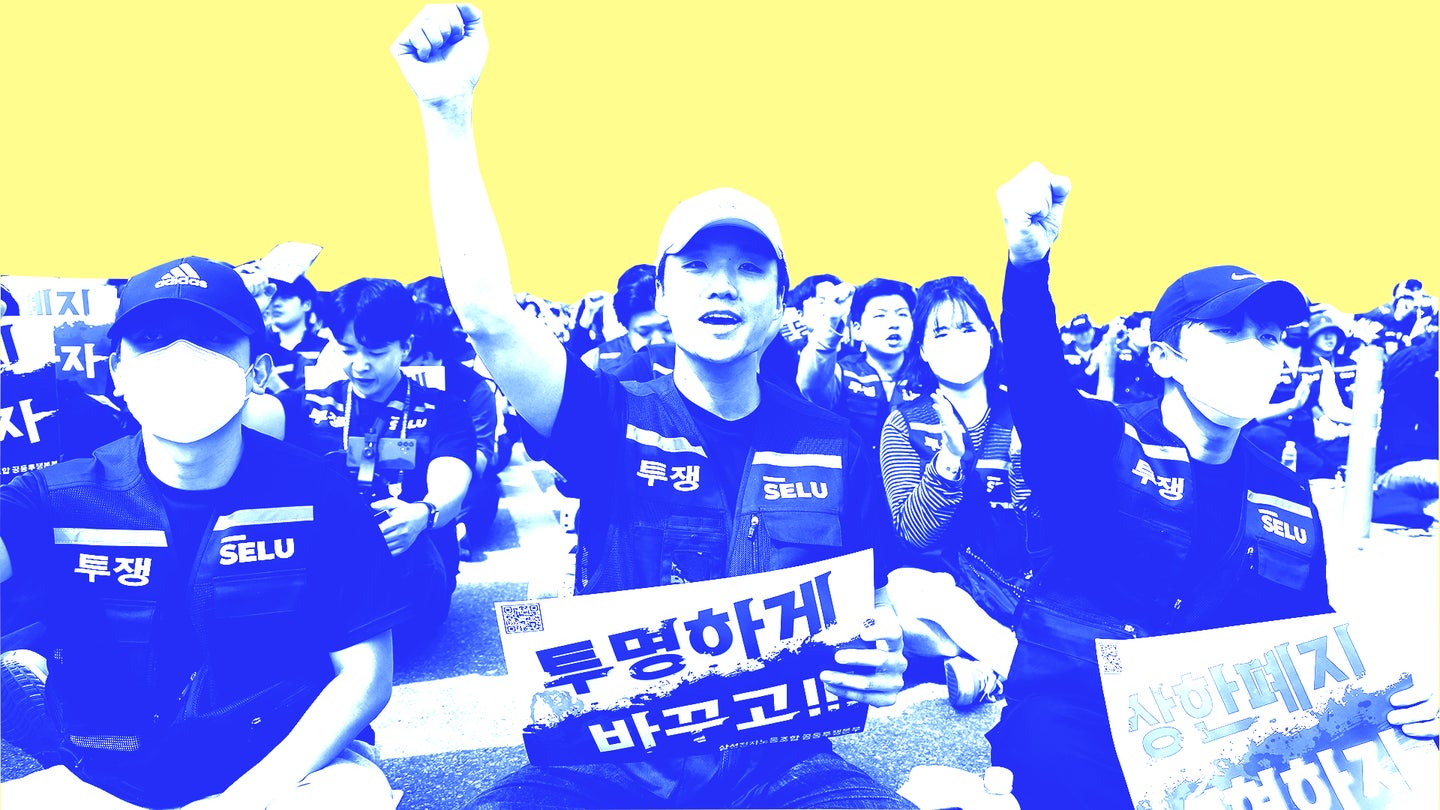 Protesters sitting on the ground raise their fists, holding signs with slogans, against a bright yellow background.