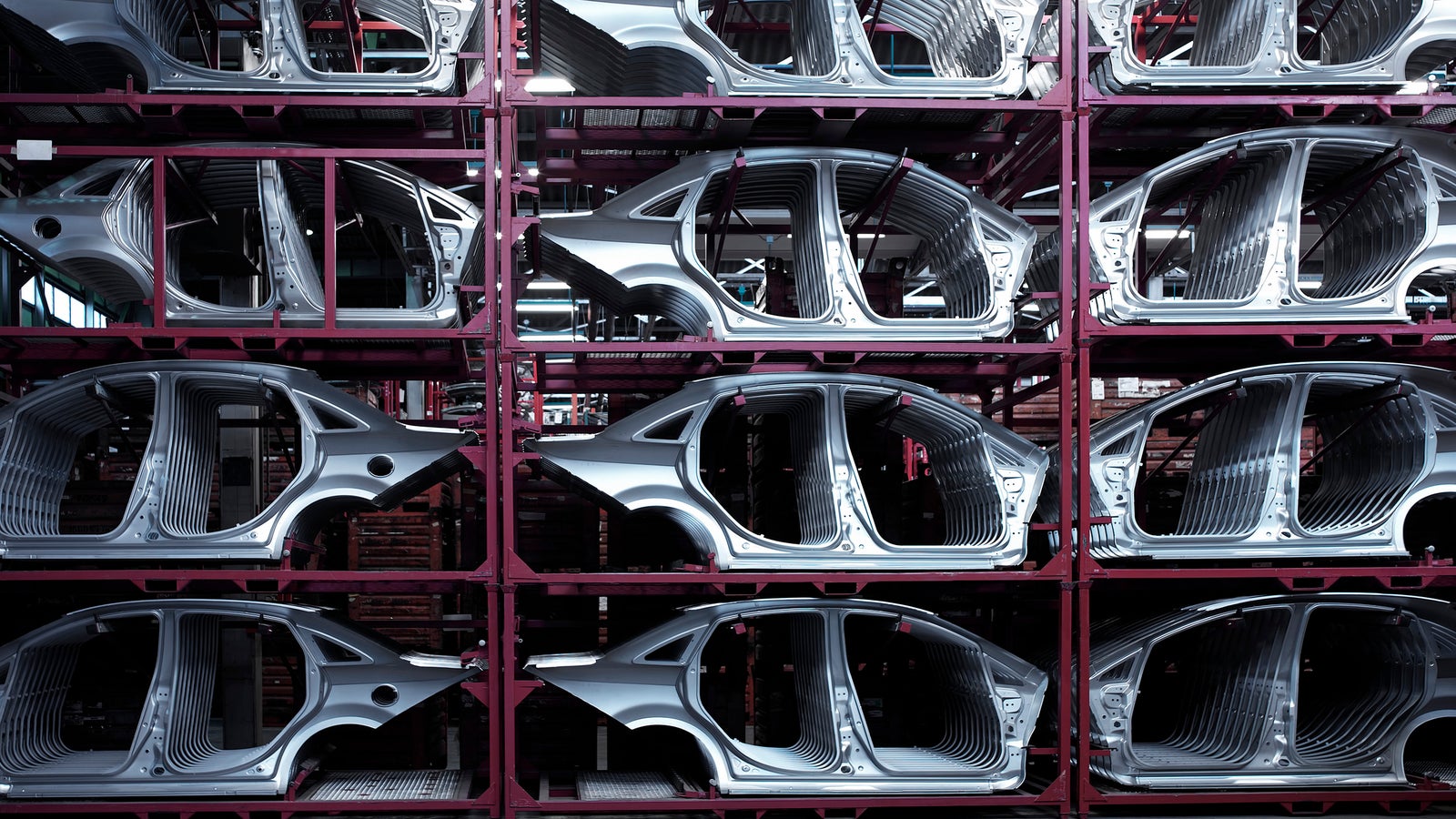 Metal car chassis stacked on shelves in a manufacturing facility, showcasing a structured and organized assembly line