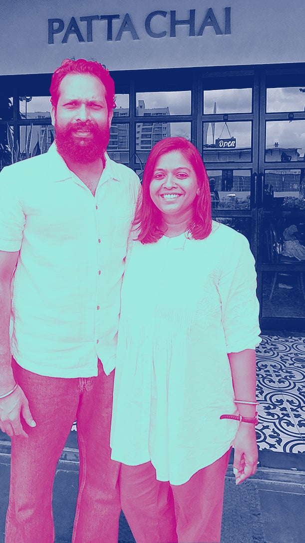 A smiling couple stands outside a restaurant named "PATTA CHAI," embracing in front of large windows and patterned flooring